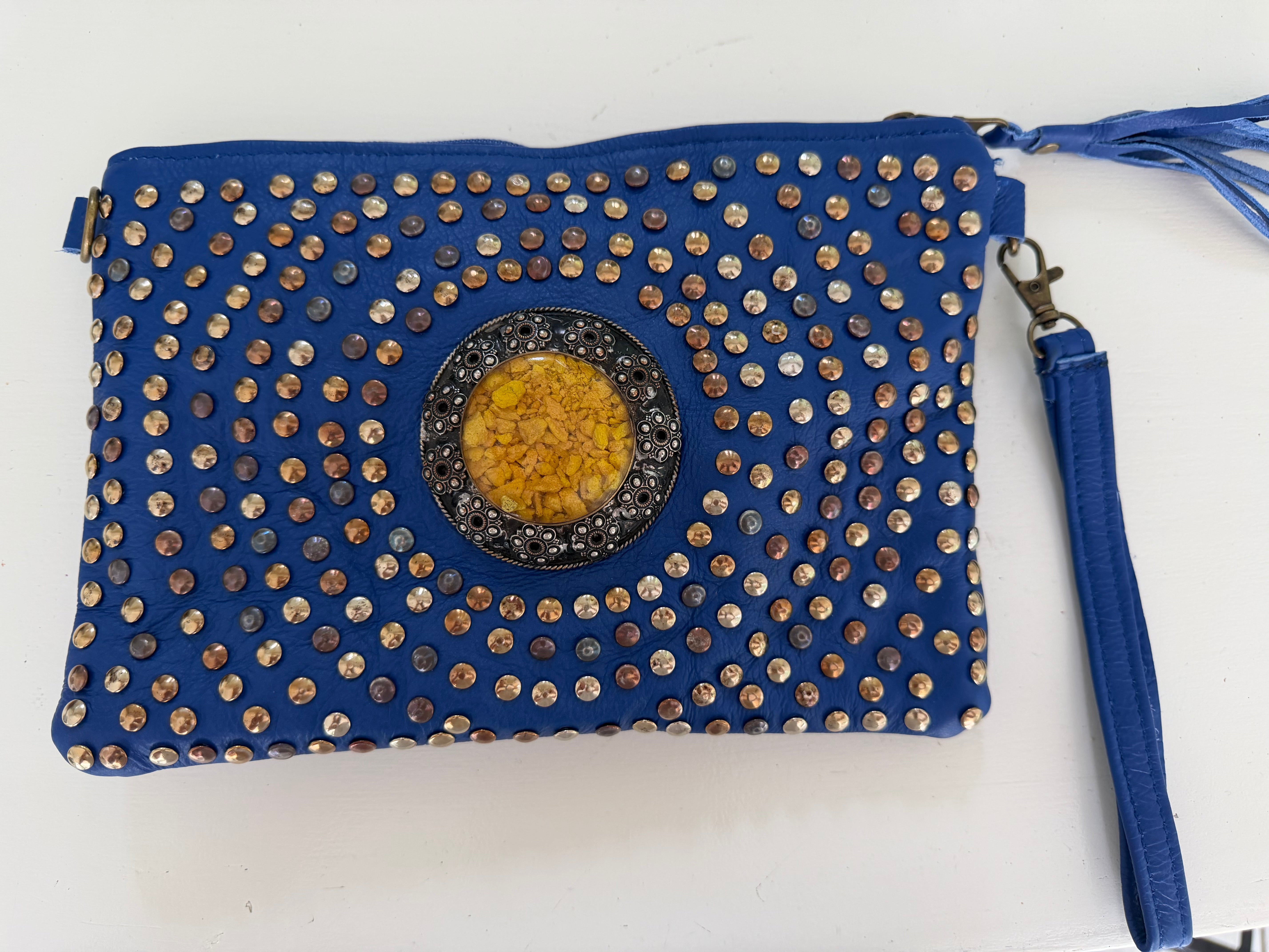 Blue leather clutch bag with gold studs and a yellow center stone